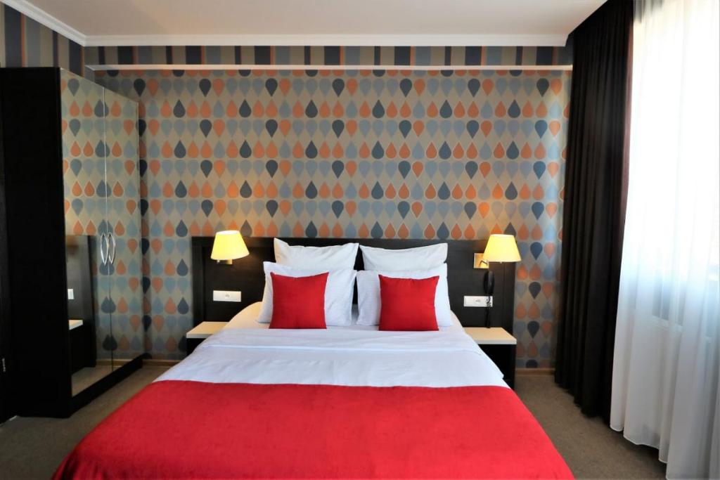 第比利斯East Gate Boutique Hotel的一间卧室配有红色的床和两个红色枕头