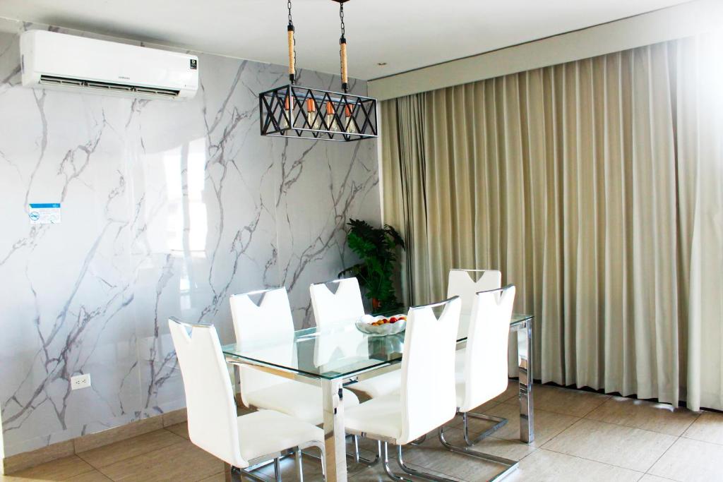 圣萨尔瓦多The Luxury Apartment的一间设有玻璃桌和白色椅子的用餐室