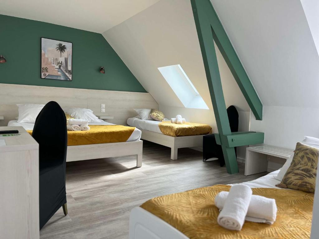 莱格勒Brit Hotel Du Dauphin L'Aigle的一间卧室设有两张床和绿色的墙壁