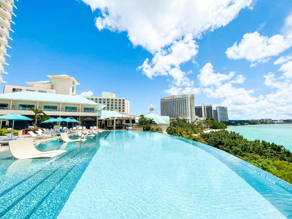 塔穆宁关岛乐天酒店的一个带椅子的大型游泳池,并享有海景