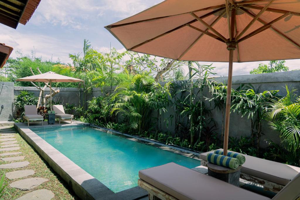 乌布Aswanaya Villas Ubud的一个带遮阳伞和桌椅的游泳池