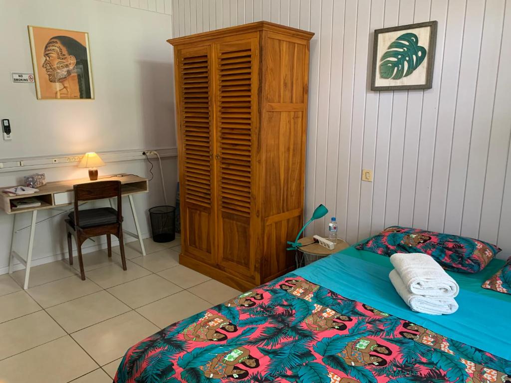帕皮提City Home Tahiti的一间卧室配有一张带木柜的床和一张书桌。