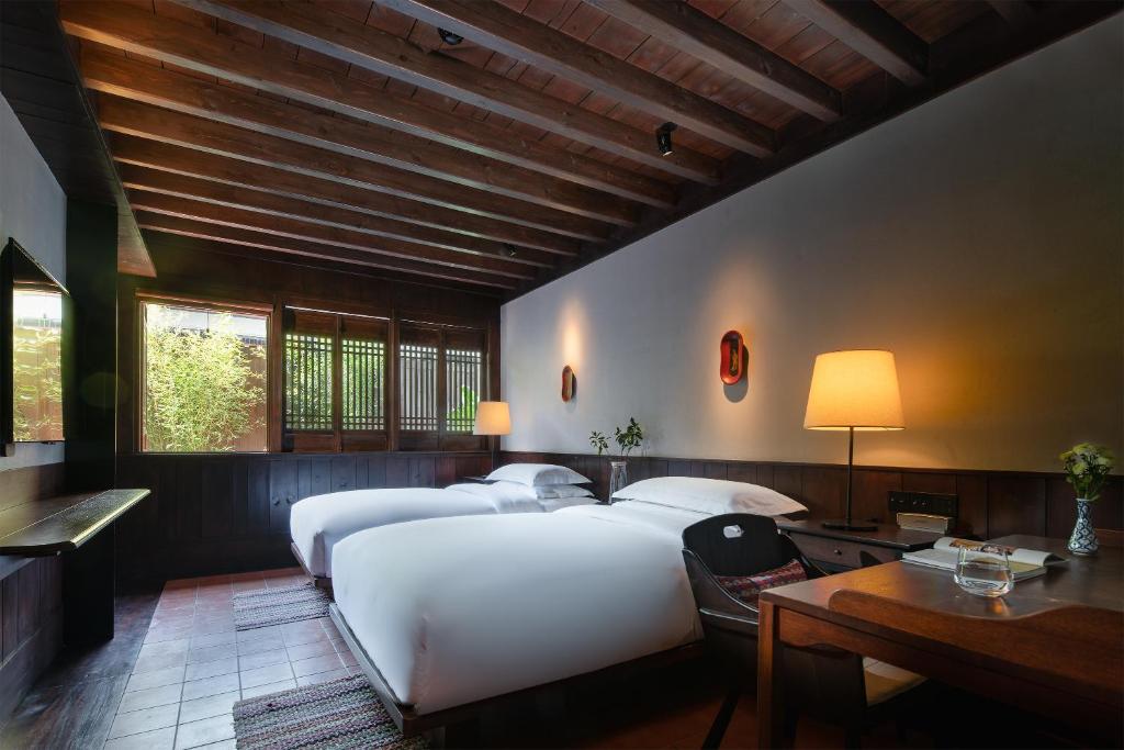 丽江丽江古城安隅酒店的一间卧室配有两张床、一张桌子和一张书桌