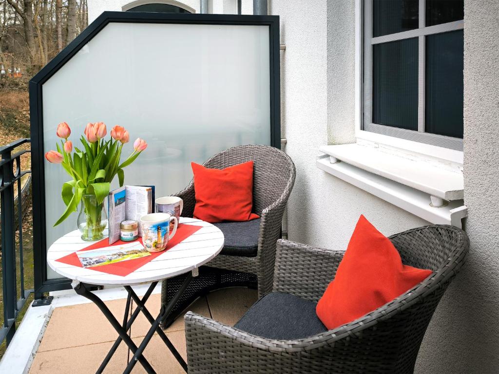 巴贝Haus Meeresblick - Ferienwohnung Kreideküste (Ref. 151261)的阳台上配有桌子和椅子,提供橙色枕头