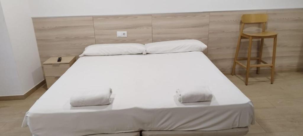 莱里达SM Apartments的一张大白色的床,位于带椅子的房间