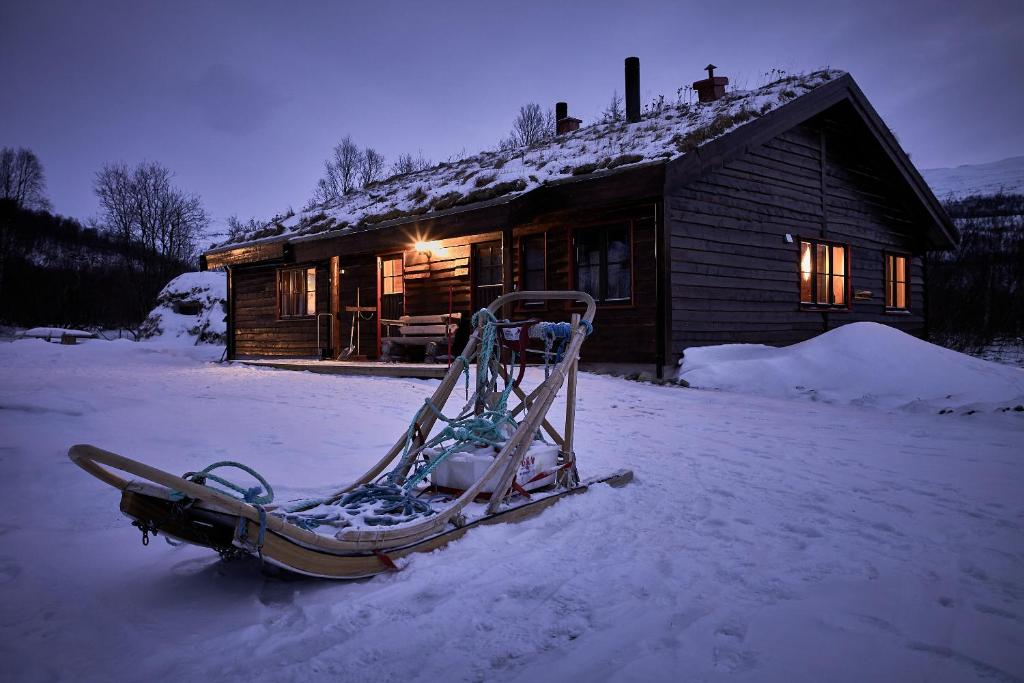 InnsetCabin Huskyfarm Innset的雪橇,坐在小屋前
