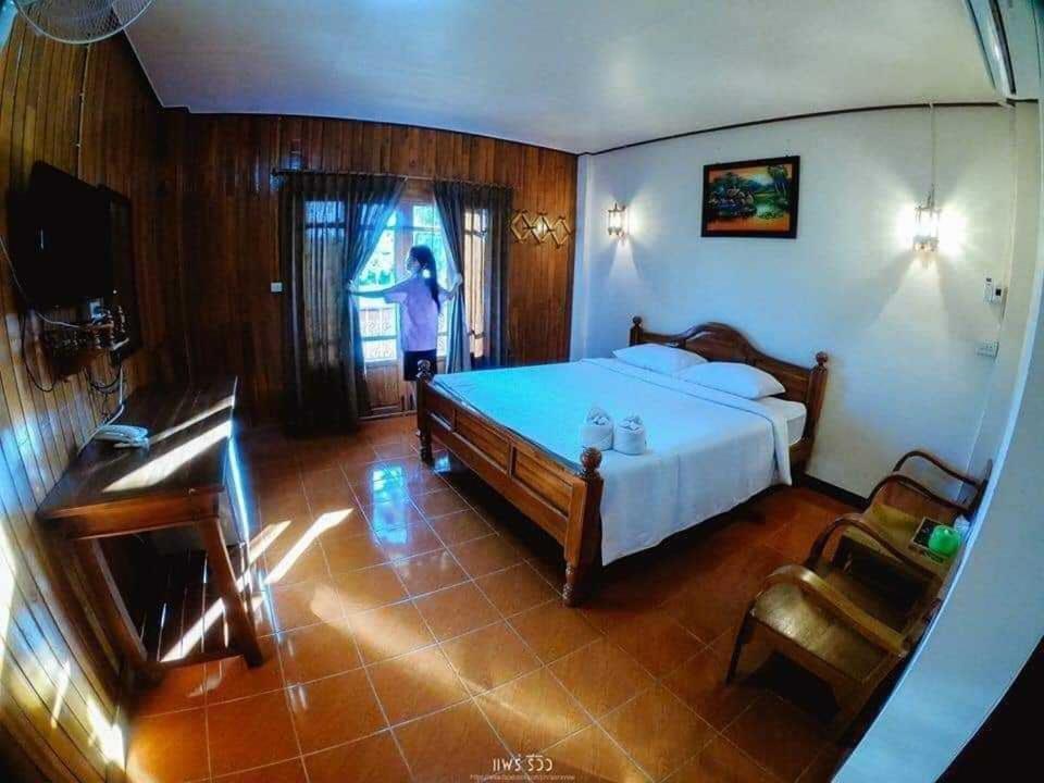 Ban Mae Laiบ้านสวนกุหลาบแก้วรีสอร์ท的卧室配有一张床,人站在窗户上