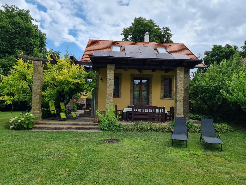 加尔多尼Duzzogó Vendégház Agárd的一座黄色房子,在院子里设有太阳能屋顶