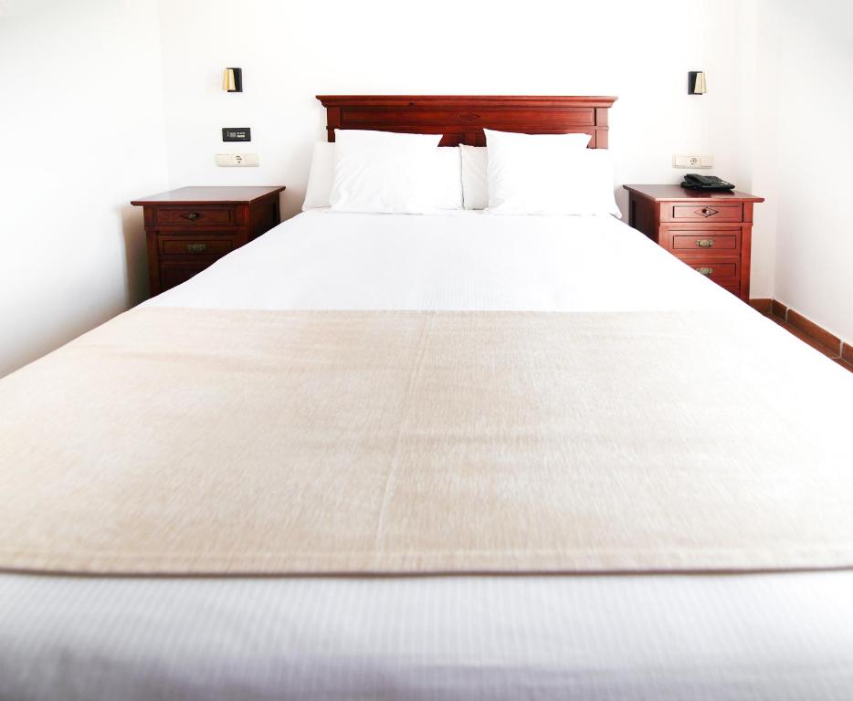 萨阿拉德洛斯阿图内斯Hostal La Muralla的一间卧室配有白色床和2个床头柜