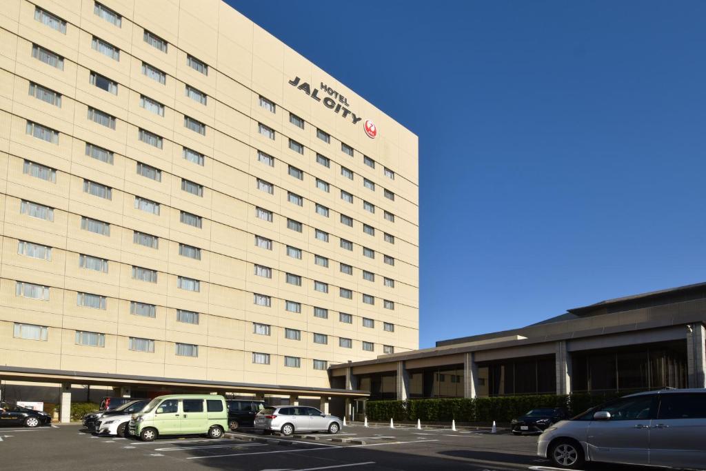 筑波筑波日航都市酒店(Hotel JAL City Tsukuba)的大型酒店,停车场内有车辆停放