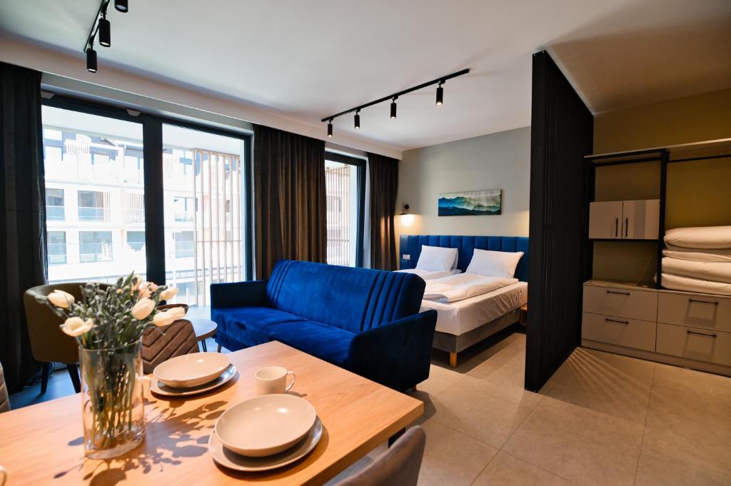 扎热切Aparthotel Laguna Beskidów的客厅配有蓝色的沙发和床。