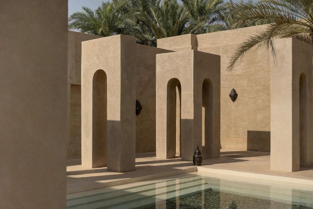 迪拜Bab Al Shams, A Rare Finds Desert Resort, Dubai的一座带游泳池和棕榈树的建筑