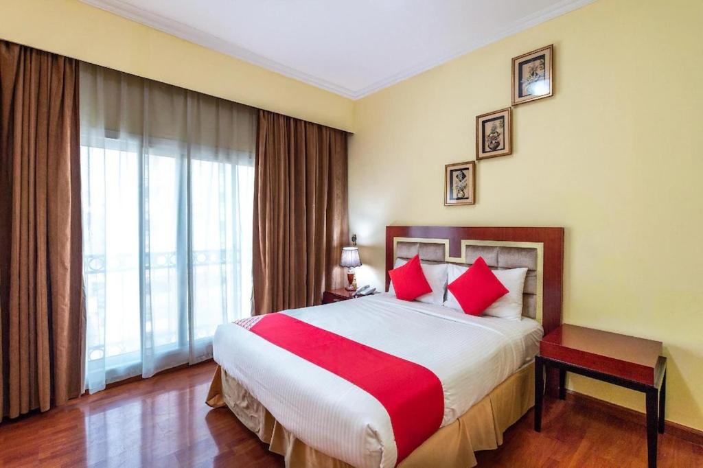 沙迦Zenith Smart Vacation Homes, Sharjah的酒店客房配有一张带红色枕头的大床