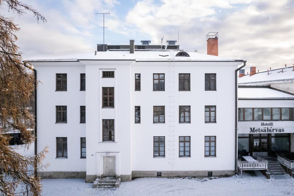 罗瓦涅米Hotel Metsähirvas的雪中的白色建筑