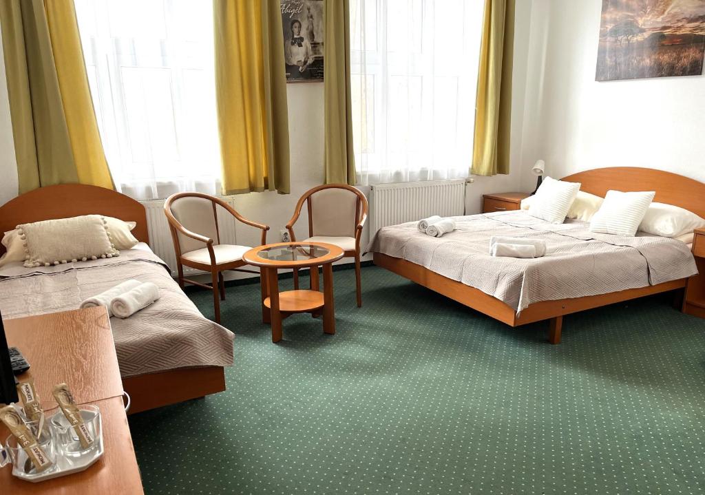 布达佩斯Broadway City Guesthouse的酒店客房带两张床和一张桌子以及椅子。