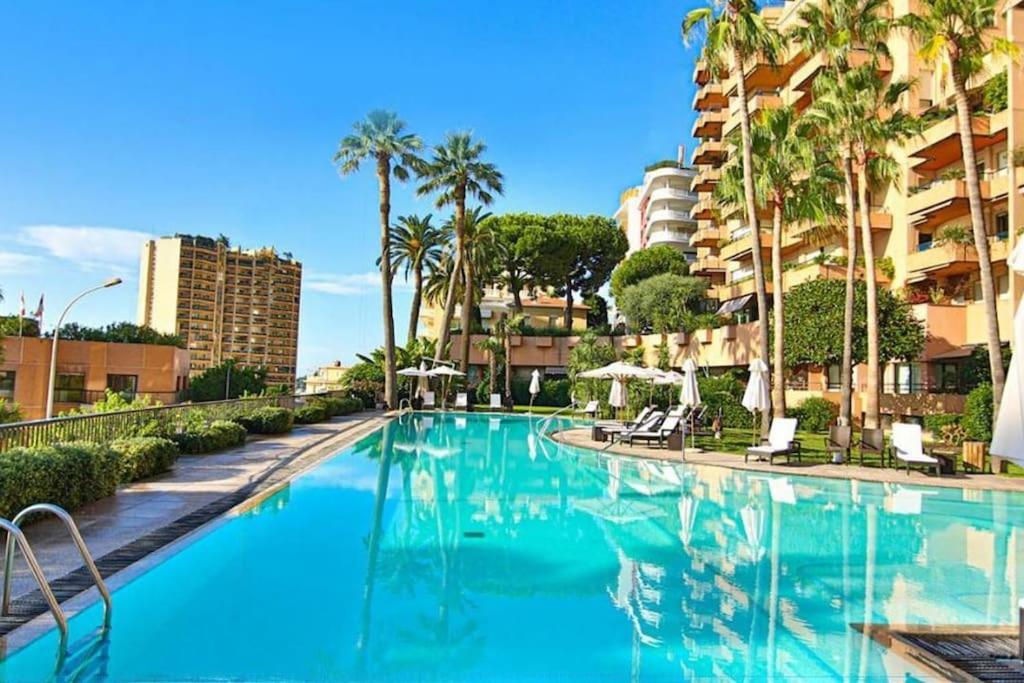 蒙特卡罗Luxurious Monaco Flat: Stunning Views & Amenities的一座棕榈树游泳池和一座建筑