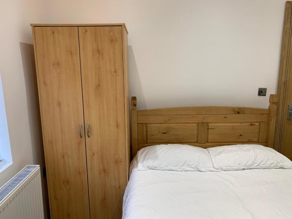 伦敦Private room, renovated with large size white desk In SE9 6PG的一间卧室配有一张床和一个木制橱柜