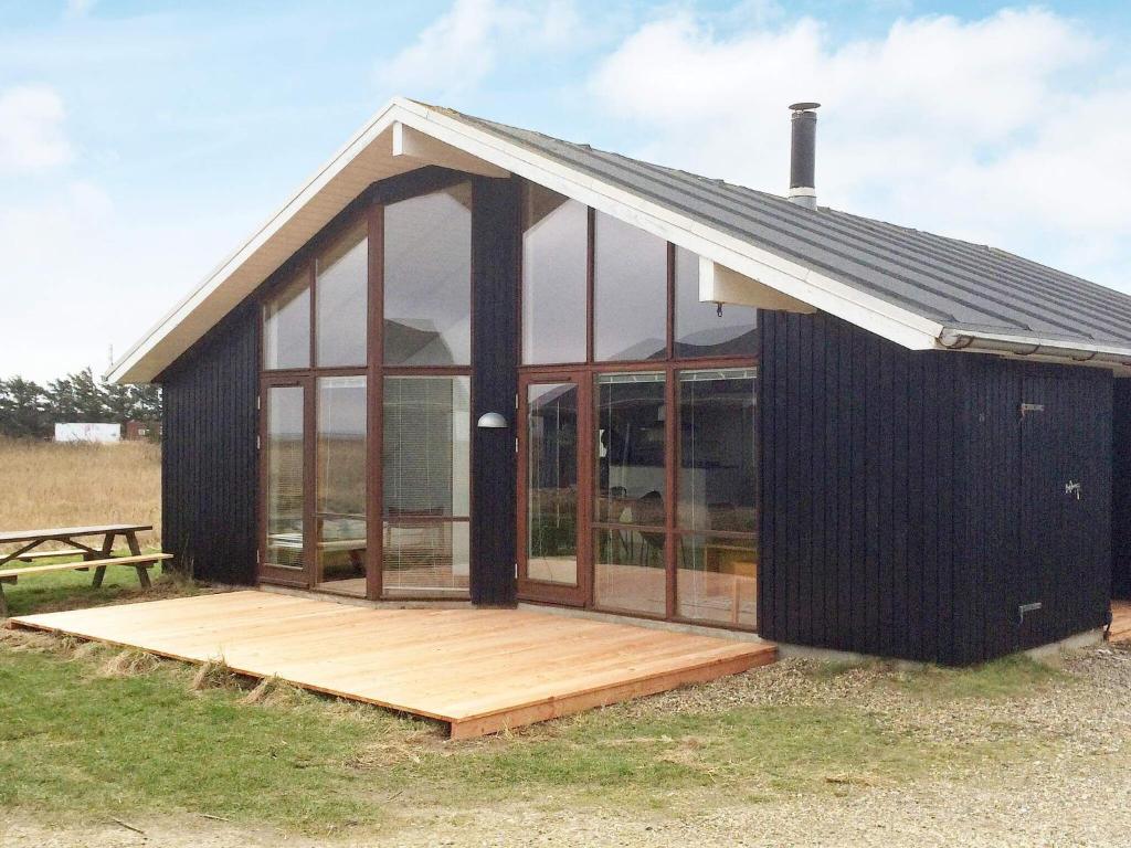 托斯明德7 person holiday home in Ulfborg的一间黑色房子,设有玻璃窗和木甲板