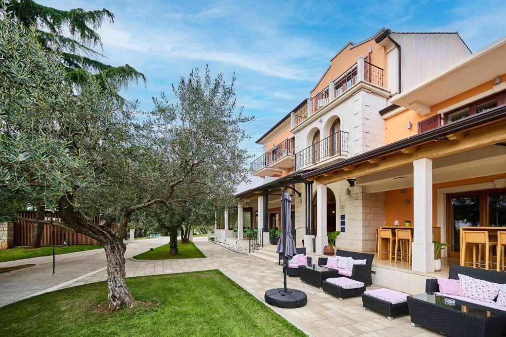 罗维尼Villa Dobravac Wine Estate的院子里有紫色家具和一棵树的房子