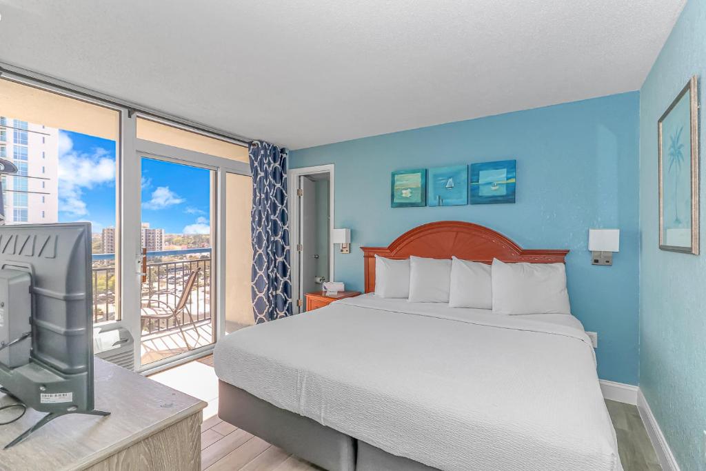 默特尔比奇Newly Renovated King Suite-Ocean Views! Boardwalk 1140的一间卧室设有一张床、一台电视和一个阳台。