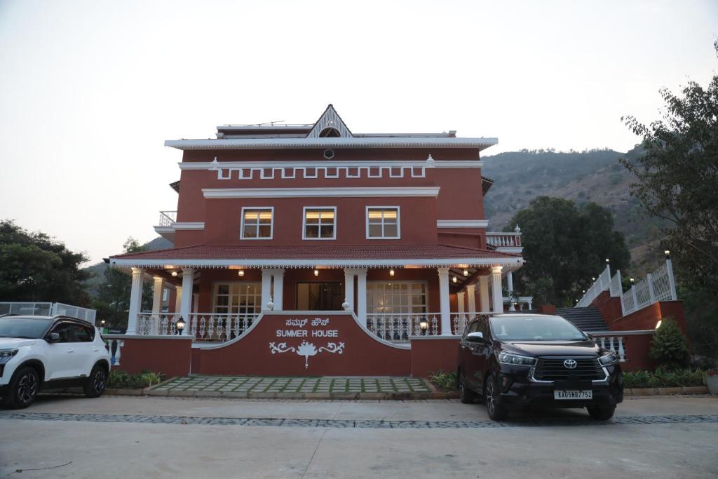 NandiSummer House Nandi Foothills的一座红色的建筑,前面有汽车停放