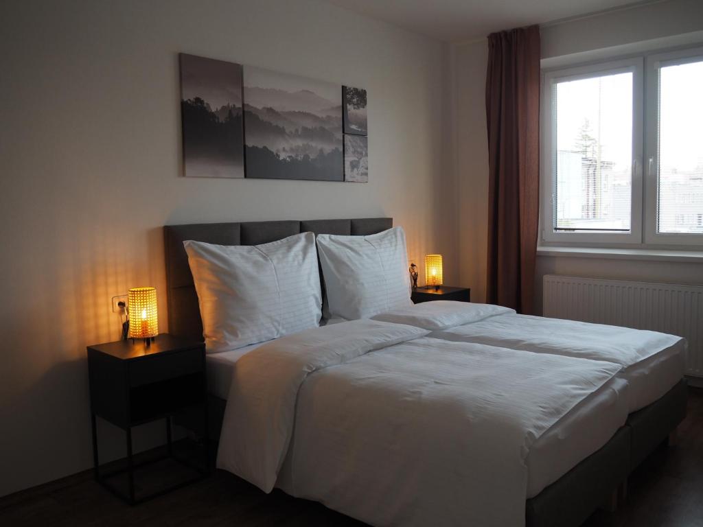 新伊钦Apartmány Abacie的一间卧室配有一张带两盏灯的床和一扇窗户。