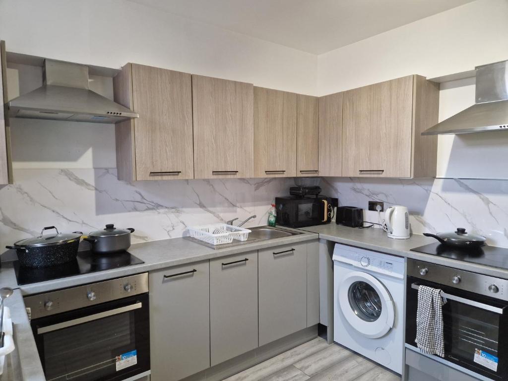 普拉姆斯特德P Williams Plumstead的厨房配有木制橱柜、洗衣机和烘干机