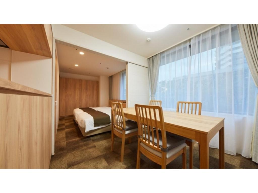 厚木Rembrandt Hotel Atsugi - Vacation STAY 41678v的配有桌椅和床的房间