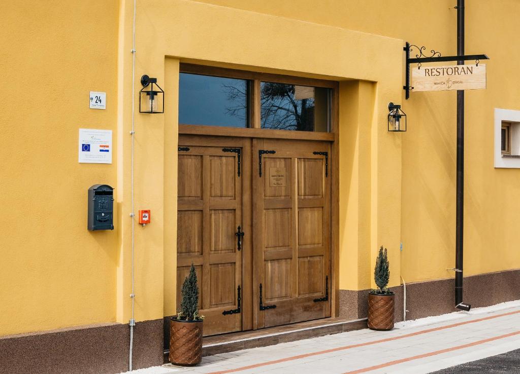 Babina GredaPansion Mihića dvori的黄色的建筑,有木门和两株植物