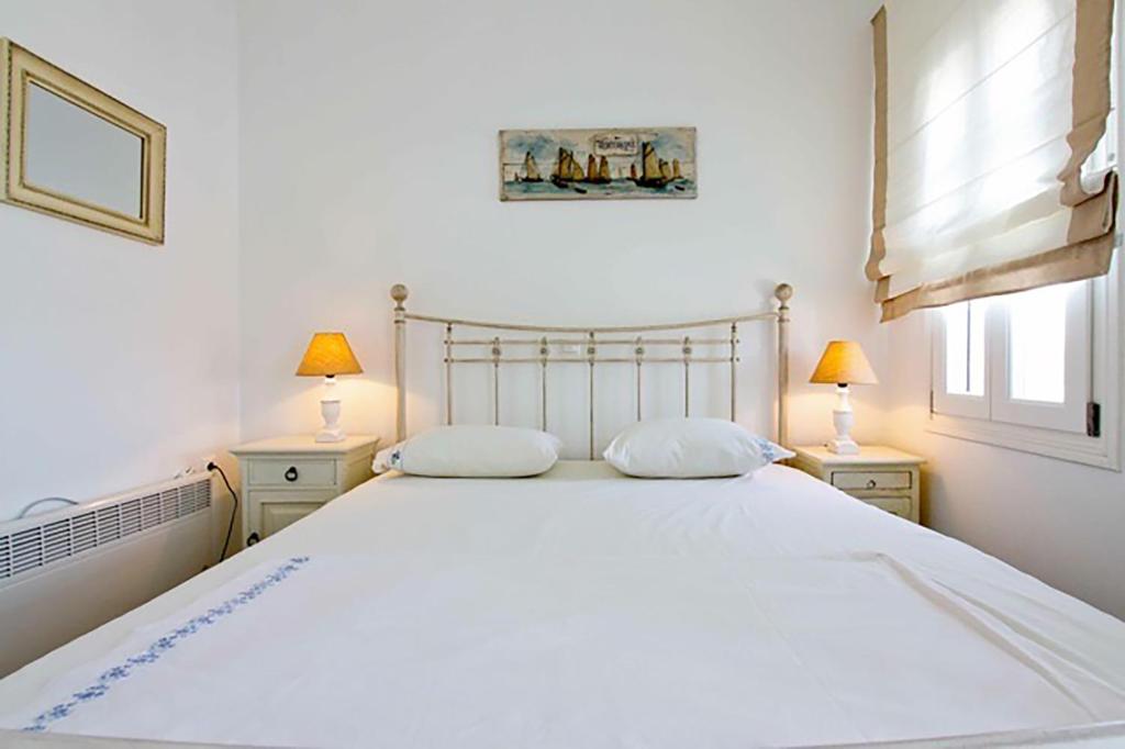 帕罗斯岛Dolce Vita Waterfront Villa, Logaras, Paros的一间卧室配有一张带两盏灯的大型白色床。