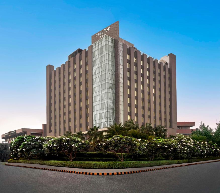 古尔冈DoubleTree by Hilton Gurugram Baani Square的一座大型酒店建筑前面有树木