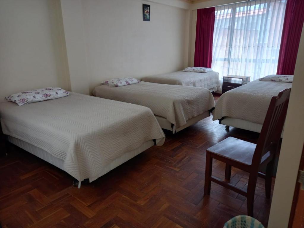 科帕卡巴纳Hostal Venegas的带三张床和椅子的房间