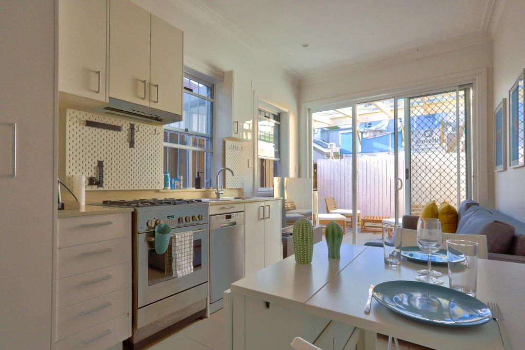悉尼2 Bedroom House Situated at the Centre of Surry Hills 2 E-Bikes Included的厨房配有白色橱柜和酒杯桌子