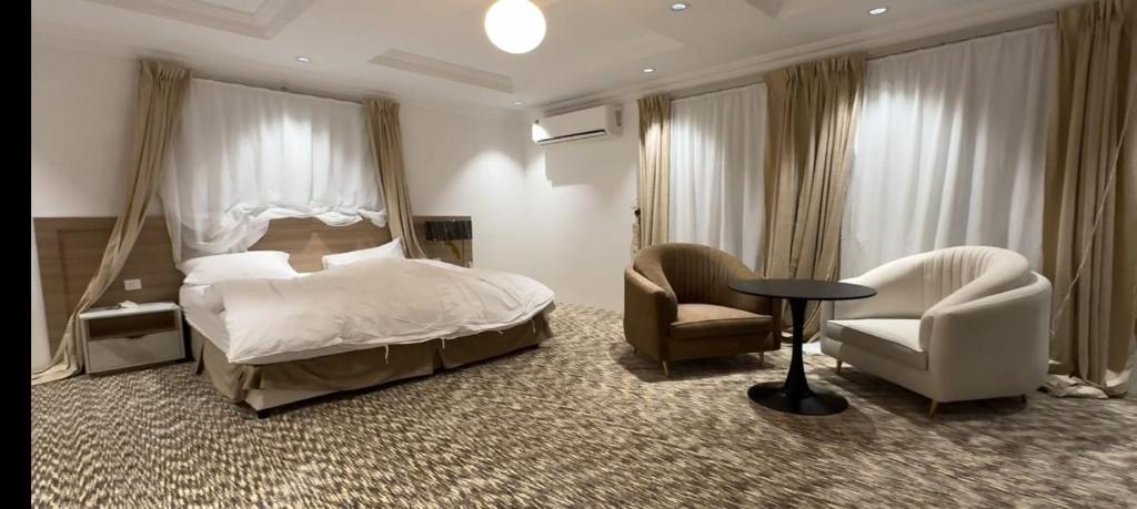 Al Bad‘Seven Star Hotel & Catering Service的一间卧室配有一张床、两把椅子和一张桌子