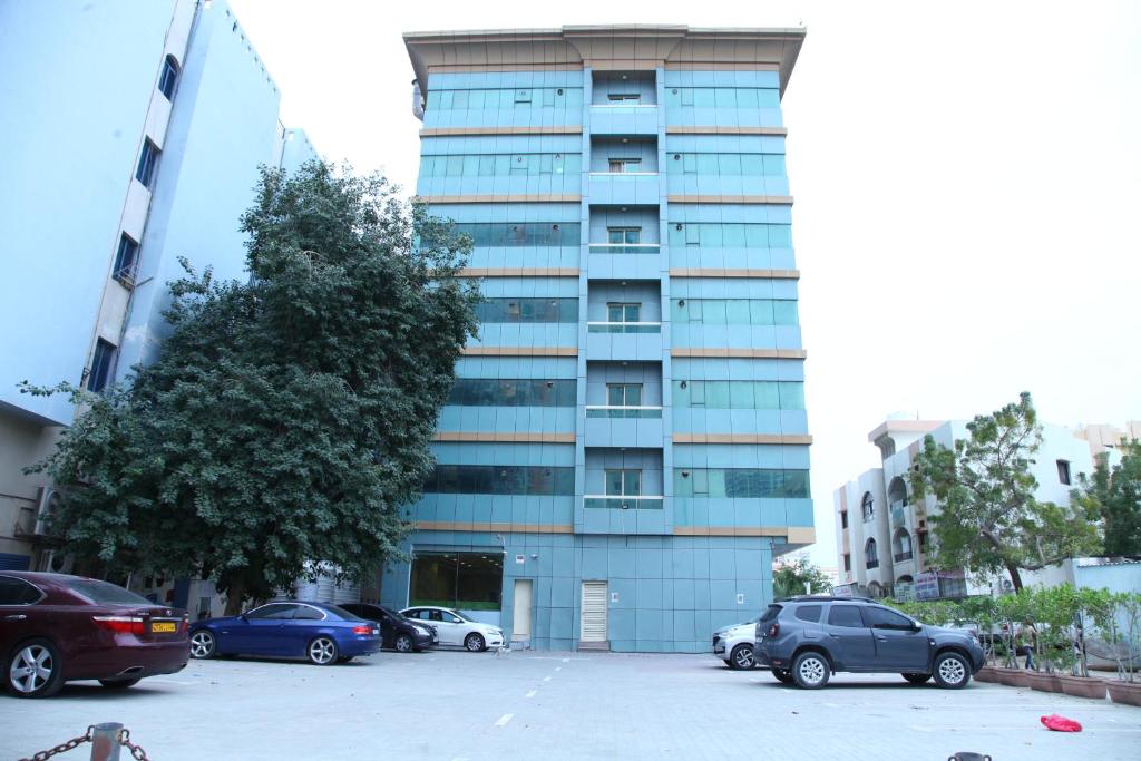 阿吉曼Zenith Smart Vacation Homes, Ajman的停车场内有车辆停放的高楼