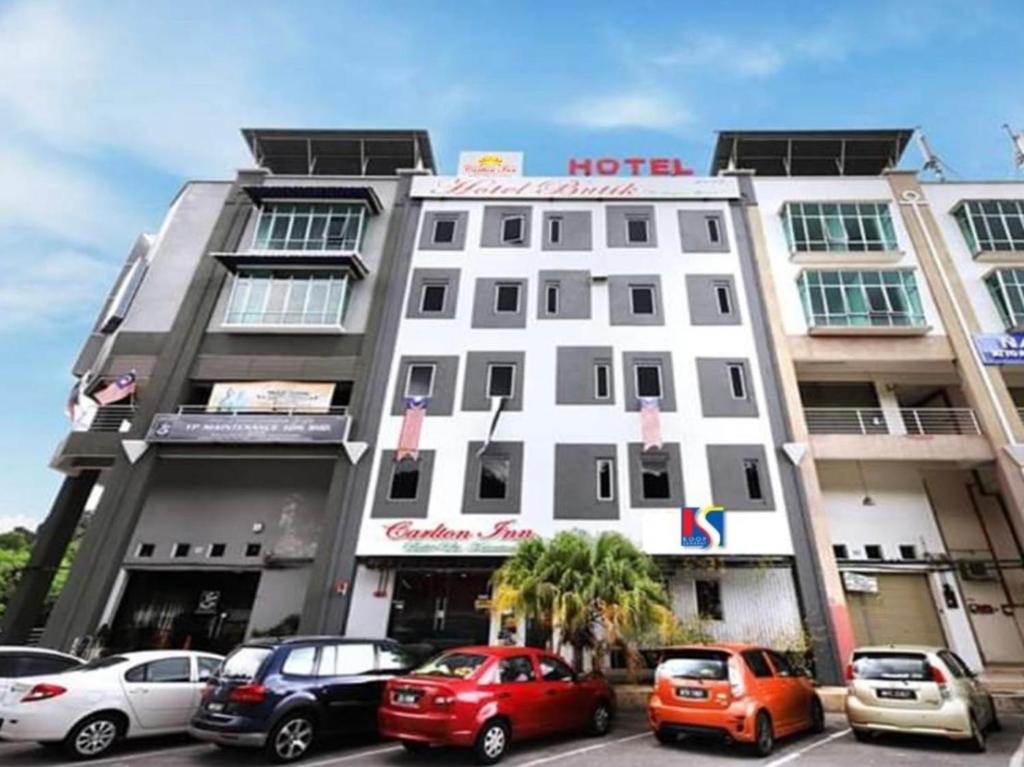 关丹OYO 89492 Carlton Inn Bukit Ubi的停车场内有车辆的旅馆