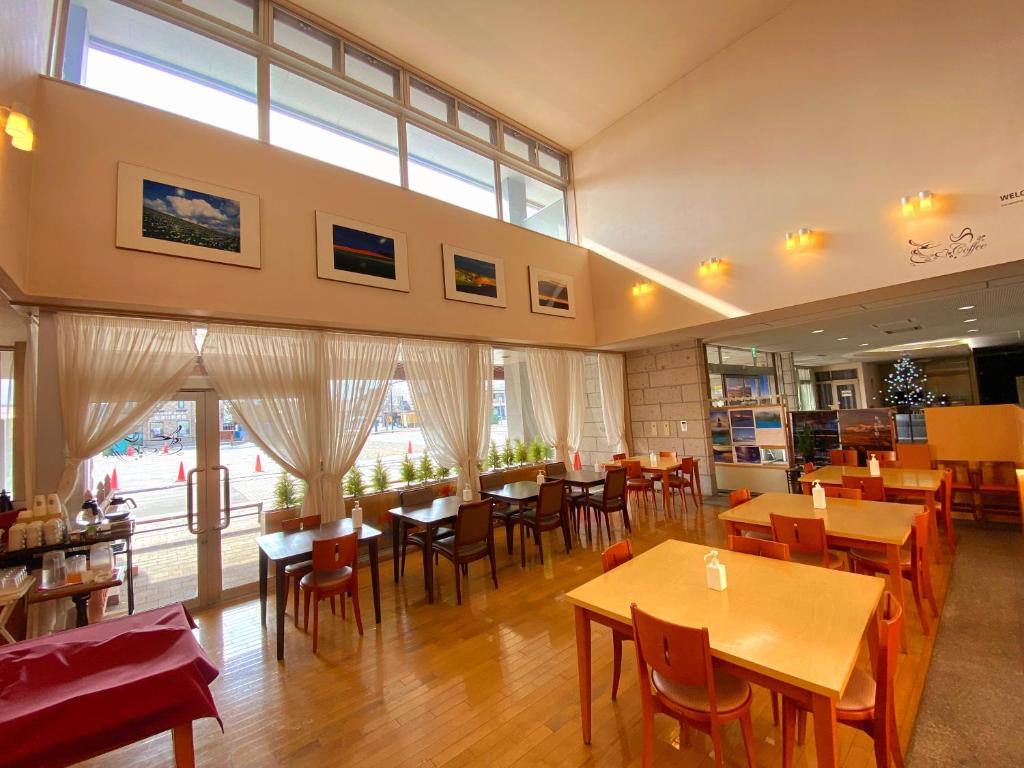 美瑛町拉温尼尔酒店的餐厅设有木桌、椅子和窗户。