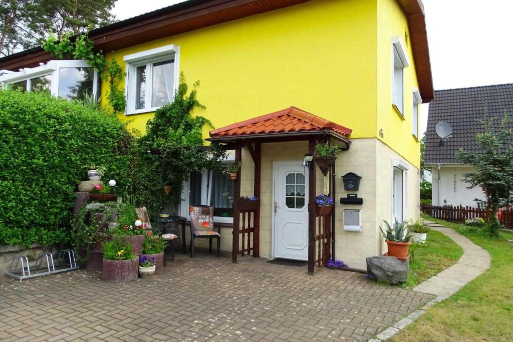 Kölpinsee auf UsedomKölp - Block`s Ferienwohnung的黄色的房子,有白色的门和门廊