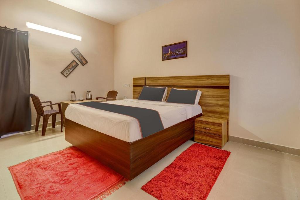 蒂鲁帕蒂Super OYO V M Inn的一间卧室配有一张带书桌的床和红色地毯。