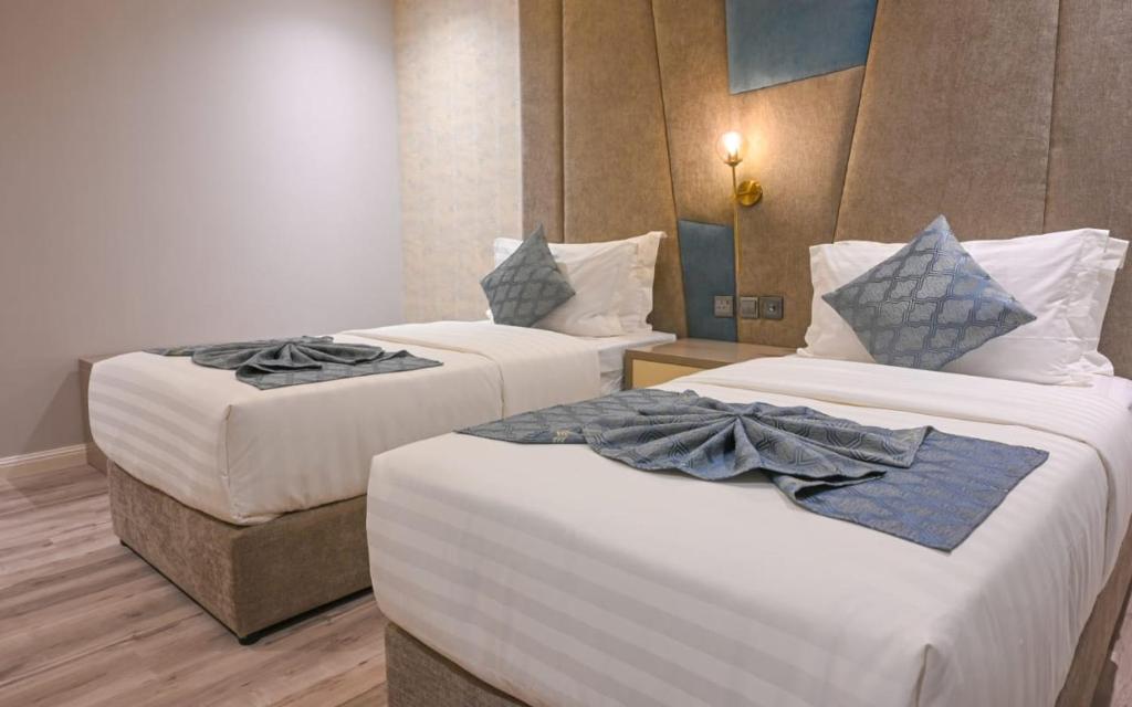 Raʼs Munaysifجاردن إيست هوتيل-الخبر的两张位于酒店客房的床,配有毛巾
