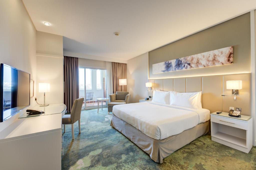 迪拜Copthorne Lakeview Hotel Dubai, Green Community的酒店客房配有一张床、一张书桌和一台电视。