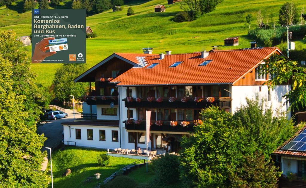 巴特欣德朗Alpenhotel Sonneck - mit Bergbahnticket的一座红色屋顶和山丘的大房子