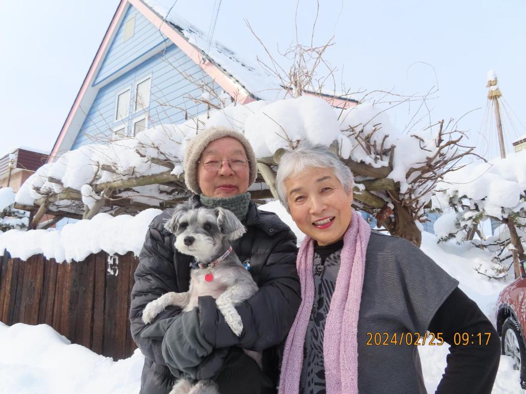 札幌民泊 B&B yoshida的一位年纪较大的女人在雪中抱着一只狗