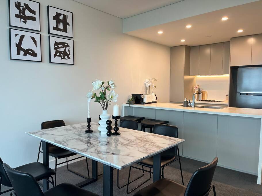 悉尼Sydney Olympic Park View Bliss Modern Design的一间带桌椅的用餐室和一间厨房