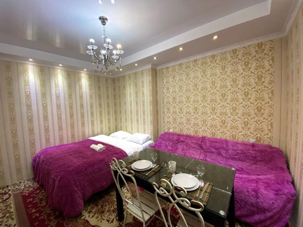 基希讷乌UrbanView Studio的一间卧室配有两张带紫色毯子和一张桌子的床。
