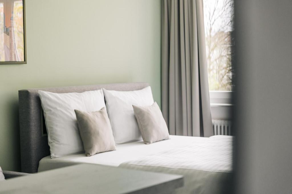 美因河畔法兰克福Homaris Apartments Frankfurt - Digital Check-In的窗户客房内的一张带白色枕头的床