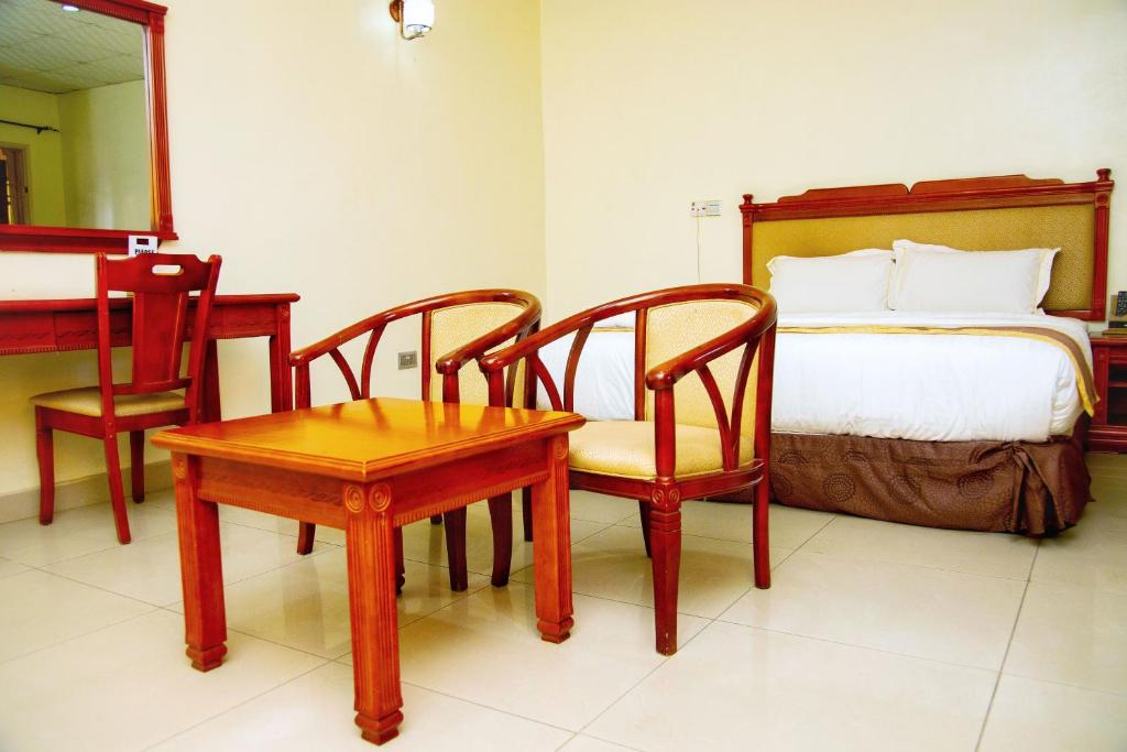 伊巴丹Classicus Inn & Apartments的卧室配有一张床和一张桌子及椅子