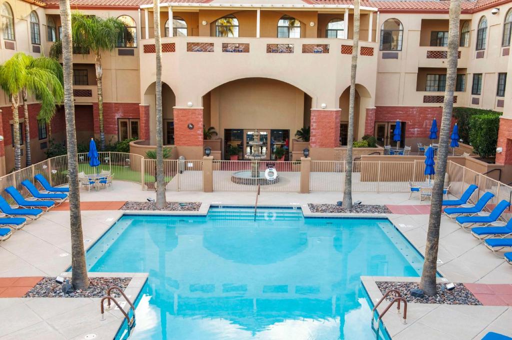 土桑Hilton Vacation Club Varsity Club Tucson的酒店前方的游泳池种有棕榈树和椅子