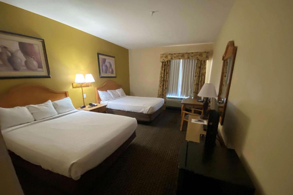 汤姆斯通Tombstone Grand Hotel, a Baymont by Wyndham的酒店客房配有两张床、一张桌子、一张床和一张沙发