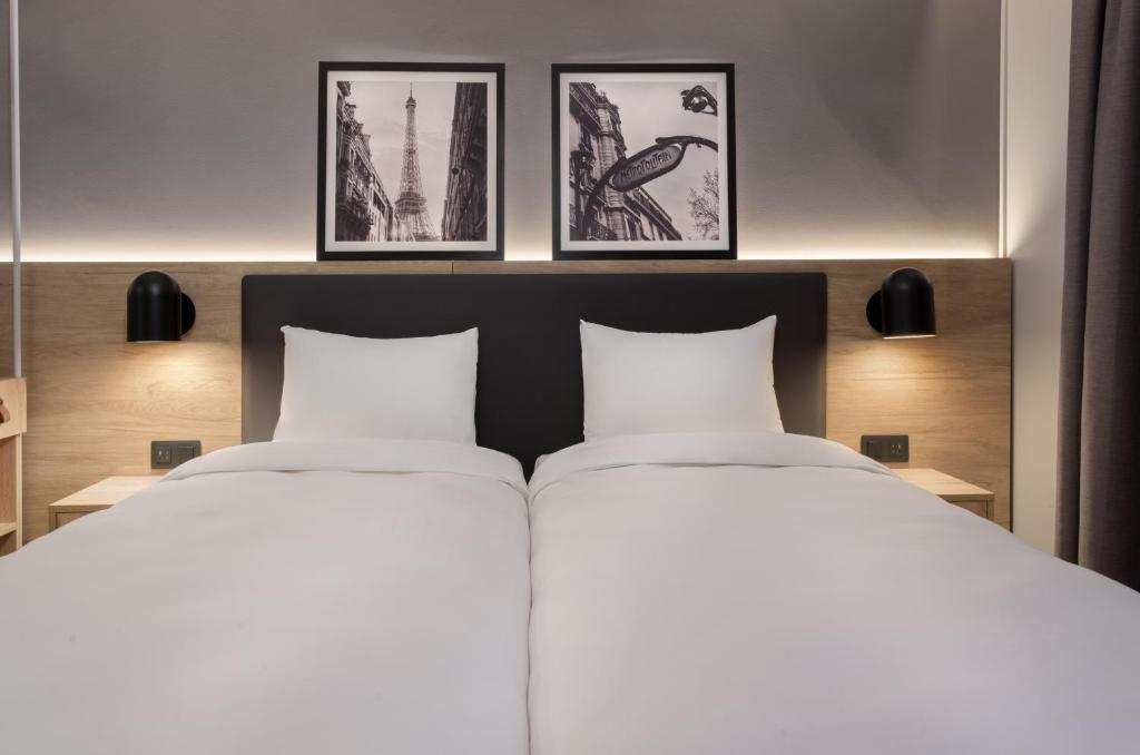 阿斯克新城钟楼里尔东维勒内弗阿斯科酒店的卧室内的两张床,墙上有三幅画